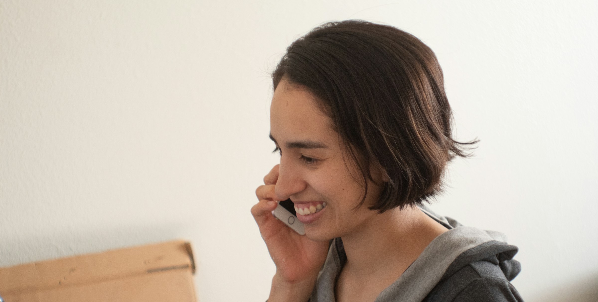 Woman in a hoodie and brown hair speaking on the phone to order an STI test